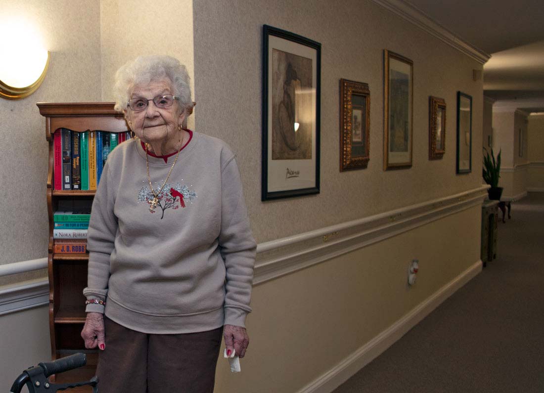 Older lady standing in hallway near bookshelf